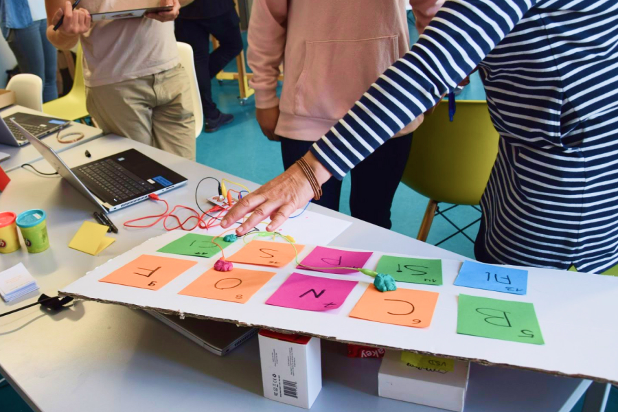 Eine Person zeigt mit einer Hand auf einen fertigen Projektaufbau eines interaktiven Periodensystems