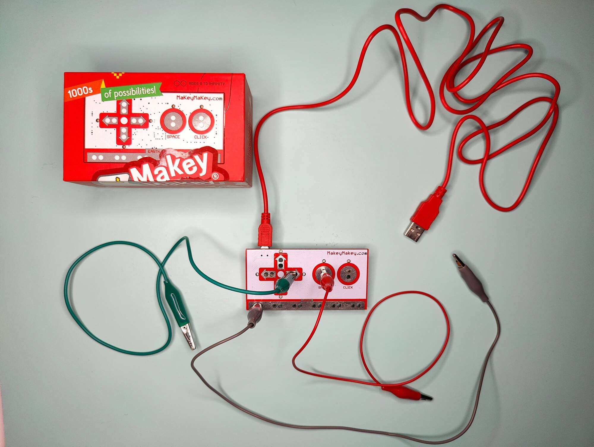 Bild von oben: Ein Makey Makey, mehrere Kroko-Clips sind an diesen angeschlossen, links daneben deren Verpackung