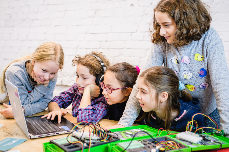 5 Kinder schauen gespannt in einen aufgeklappten Laptop, neben dem Laptop steht eine SenseBox