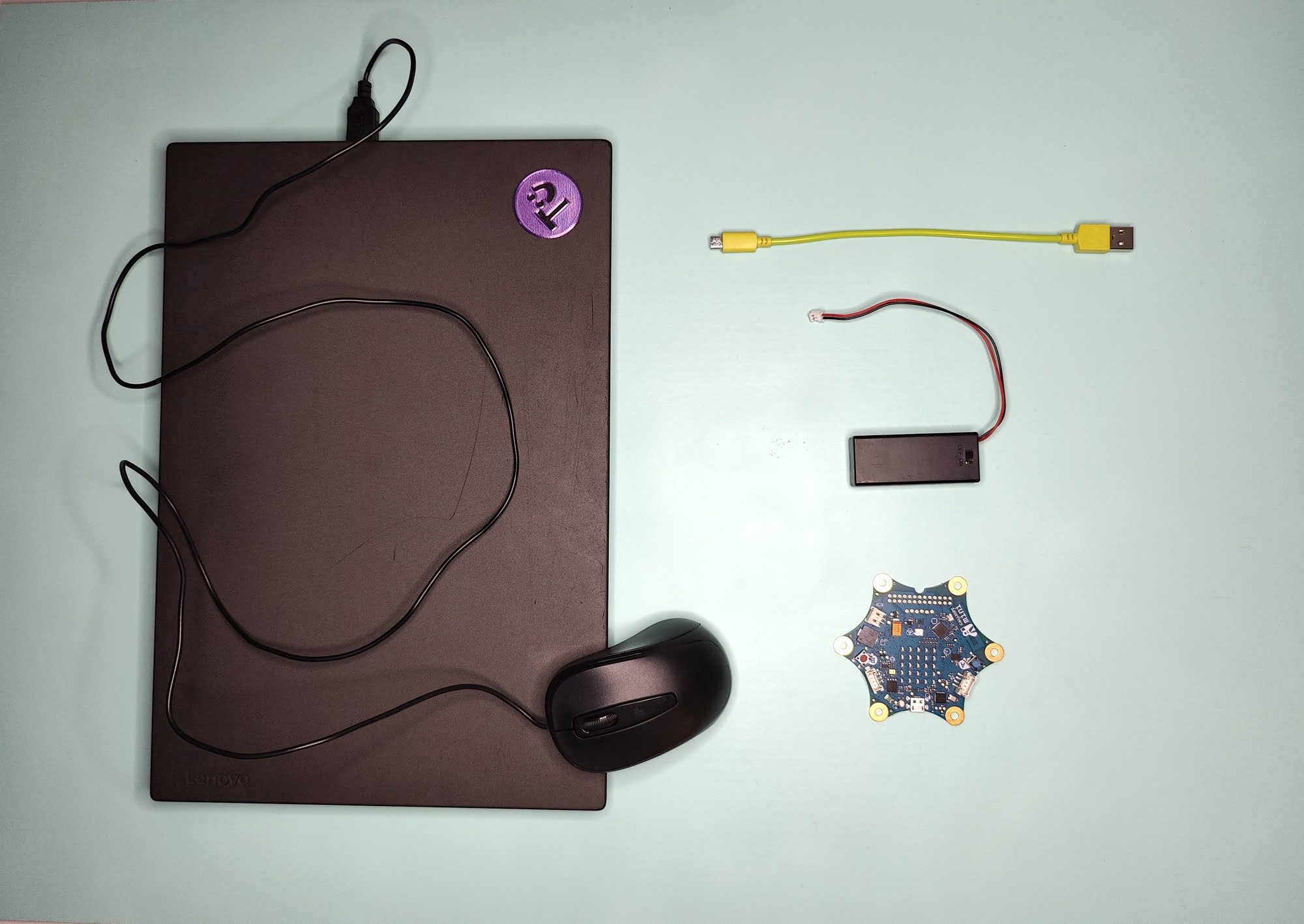 Ein Laptop mit Maus, ein Calliope mini, ein USB-Kabel, ein Batteriepack
