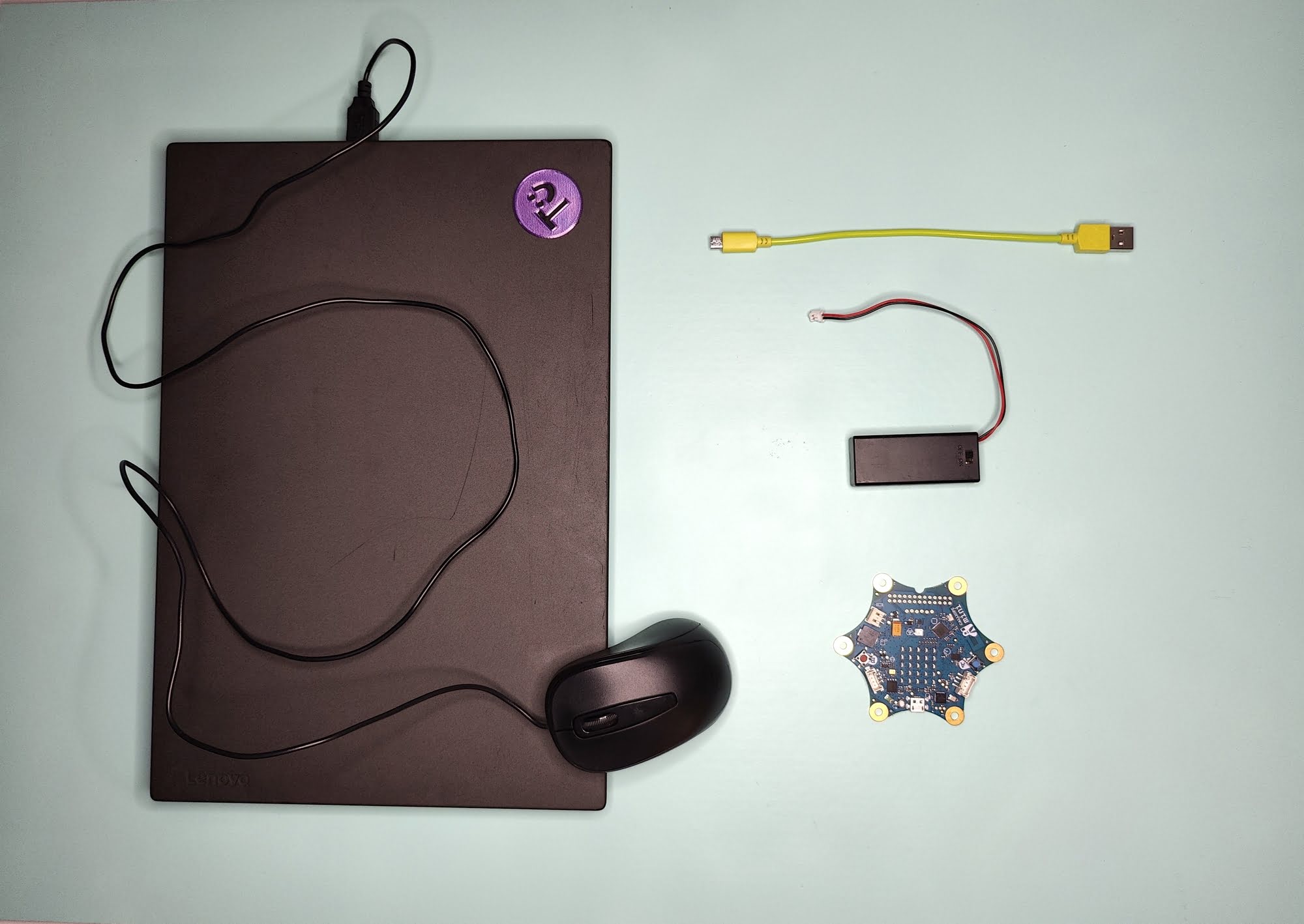 Ein Laptop mit Maus, ein Calliope mini, ein USB-Kabel, ein Batteriepack