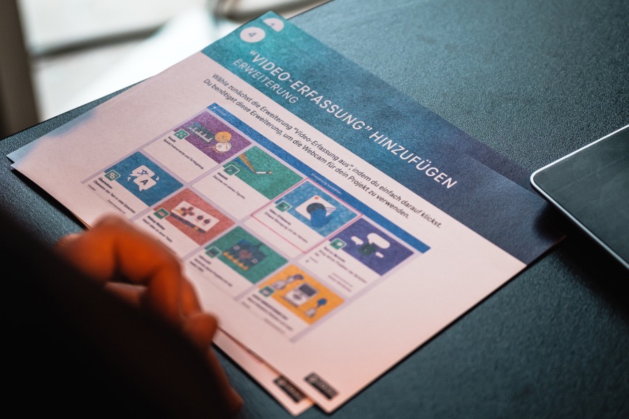 Ein Set Lernkarten liegen auf einem Tisch. Eine Person sitzt an einem Tisch und schaut in die Lernkarten.