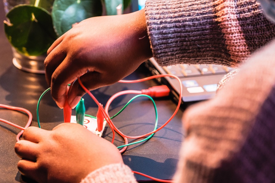 Ein Kind verbindet das Makey Makey mit verschiedenen Krokoklemmen