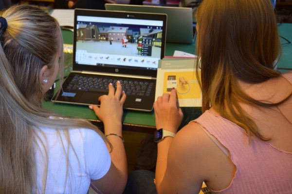 Zwei Mädchen arbeiten an einem Computer an einem Delightex-Projekt. Ein Mädchen hält eine Delightex-Lernkarte in ihren Händen