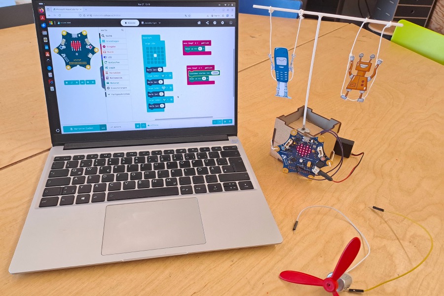 Ein selbstgebautes Karussell mit einem Calliope steht neben einem Laptop, auf dem MakeCode geöffnet ist.