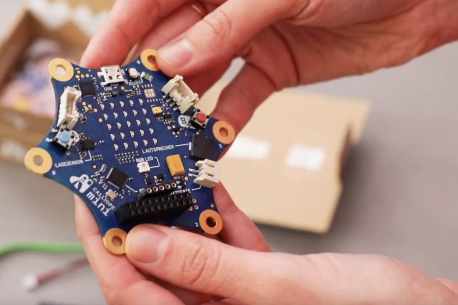 Zwei Hände halten einen Calliope mini in die Kamera